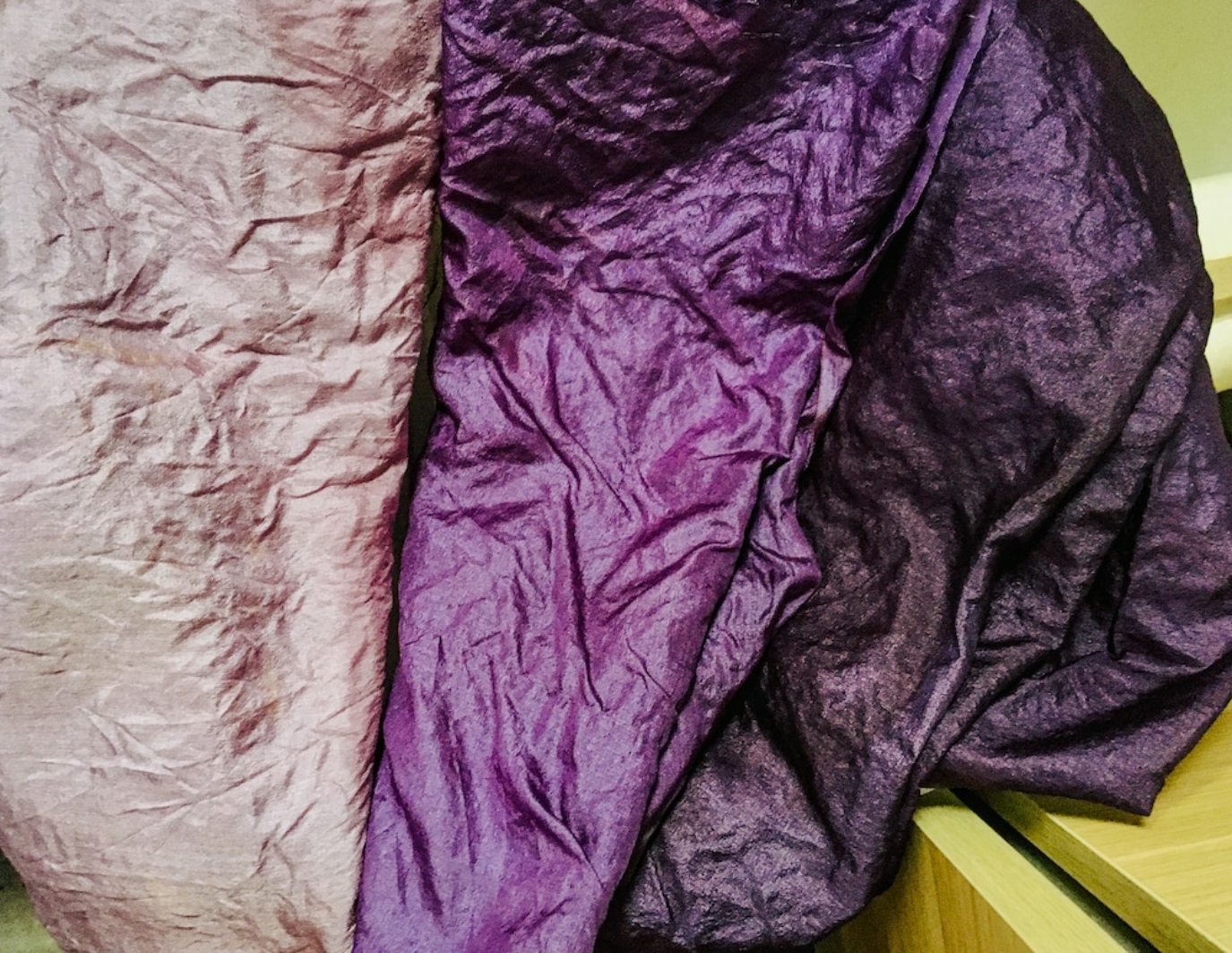 A close up look of the hand dyed materials used to construct the flowers for the Dream Puppet. Wrinkles silk that is dark purple, mainly, with some lighter lavender shade to the left of the frame.