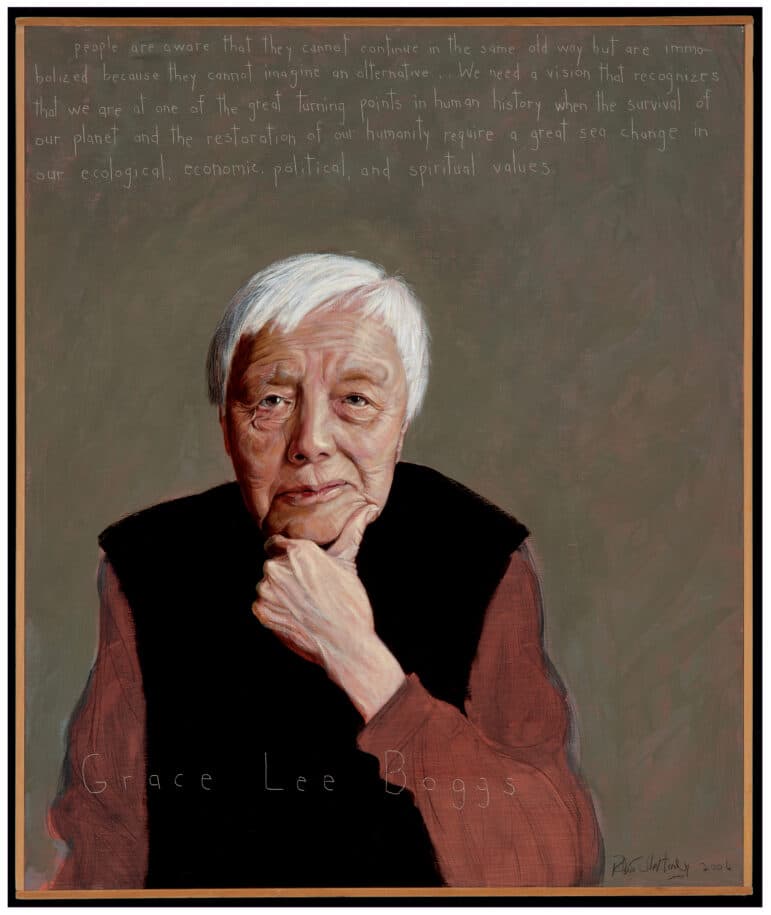A portrait of Grace lee Boggs, and eldery woman with short white hair. She is wearing a long sleeve black shirt under a black vest. Her background is gray. 