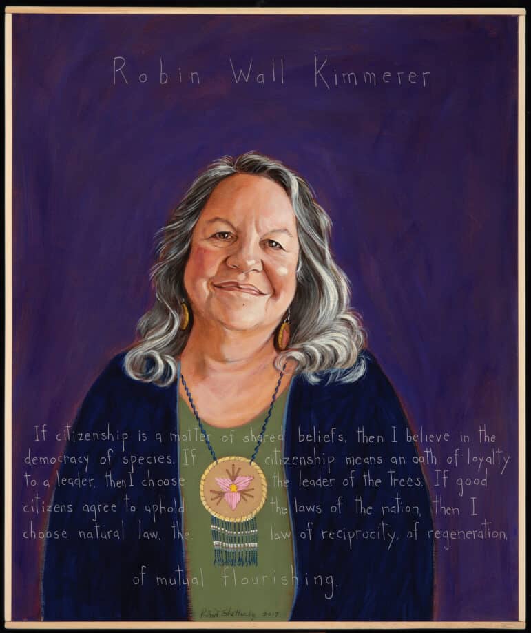 A portrait of Robin Kimmerer, an older woman with shoulder length gray hair. She wears a dark blue jacket over a green shirt, and she also wears a beaded medallion necklace. Her background is purple. 